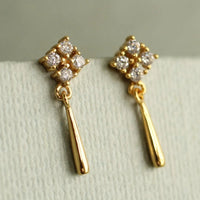 A pair of gold earrings with diamond-encrusted dangling elements.