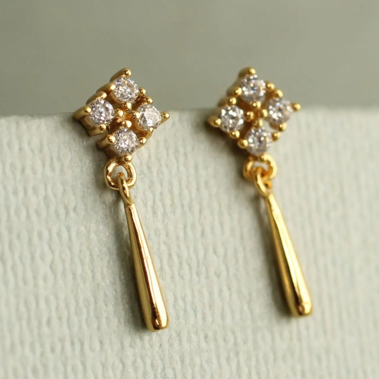 A pair of gold earrings with diamond-encrusted dangling elements.