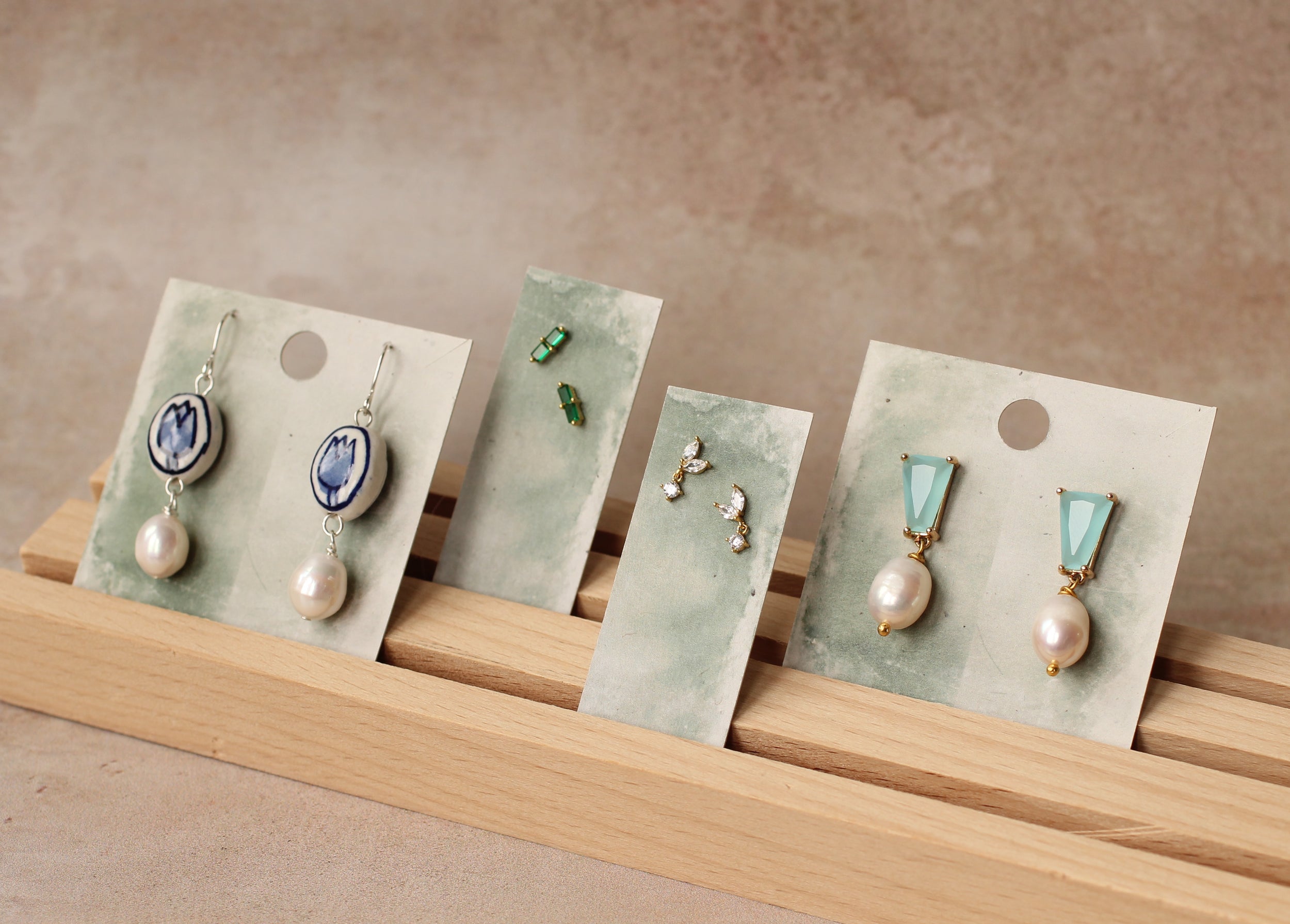 A display of various earrings on a wooden stand, each on a card.